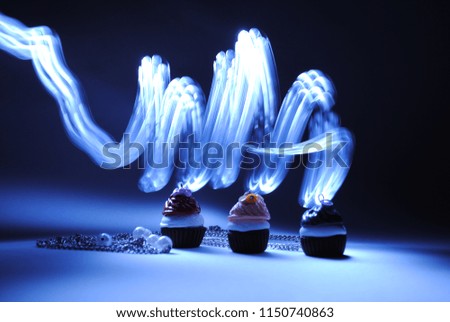 Necklaces in the shape of cupcakes with smoky light painting swirls in the background