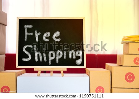 Black board with free shipping word and  packing brown parcels box at home office. seller prepare product ready for deliver to customer. Online selling, e-commerce Start up free delivery  concept.