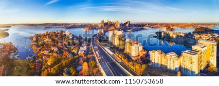 Wide aerial panorama of Sydney city CBD landmark around Harbour viewed from North Sydney along Warringah freeway lit by warm morning light.