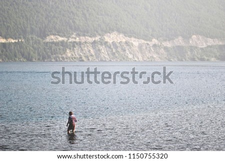 One man fishing in a river during the day.