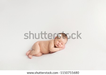 Sleeping newborn girl on a white background. Photoshoot for the newborn. 7 days from birth. A portrait of a beautiful, seven day old, newborn baby girl