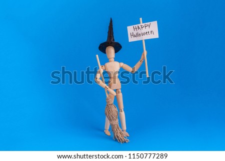 Halloween witch holding picket sign Happy Halloween on sign wooden jointed dummy figure with black witch hat and broom on blue background