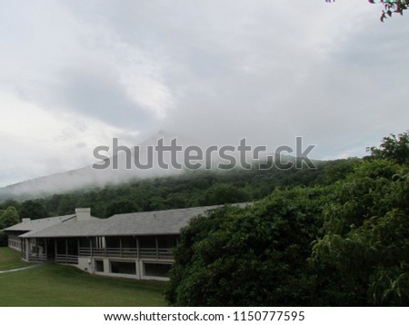 clouds begin to hide sharp top peak as rain moves in to housing at Peaks of Otter, Bedford, VA, USA