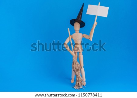 Witch Holding blank picket sign Halloween black witch hat and broom held by wooden manikin jointed doll on blue background