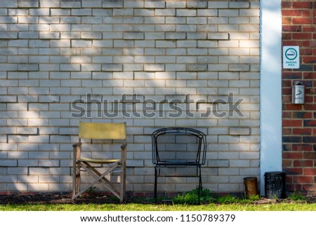 Outdoors smoking area at an old manufacturing building with a couple of old chairs and Smoking Area sign