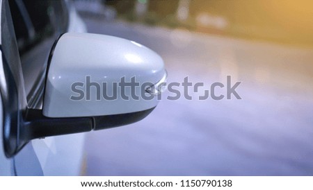 Selective focus on Wing mirror or Side mirror of white Car on warm light with blurred bokeh at the dark night City road with copy space.