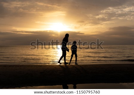 Mother and son playing on the beach during sunset in tropical island