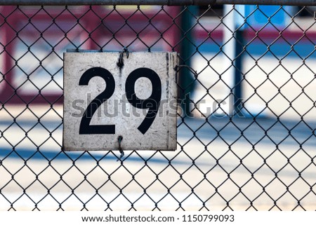 white sign on a chain link fence with the number 29 and worn dirt and grunge