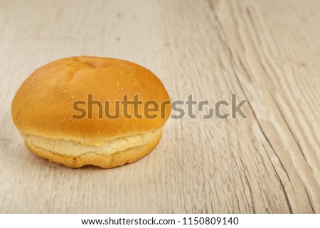 Fresh ruddy bun on a wooden background.