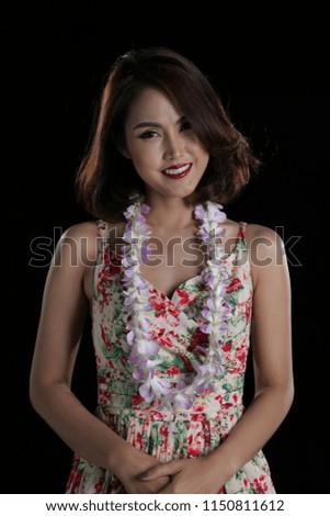 Beautiful woman half body posing with orchid flower lei on black background.