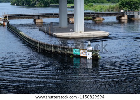 Barrier in Water with Signs Near Bridge