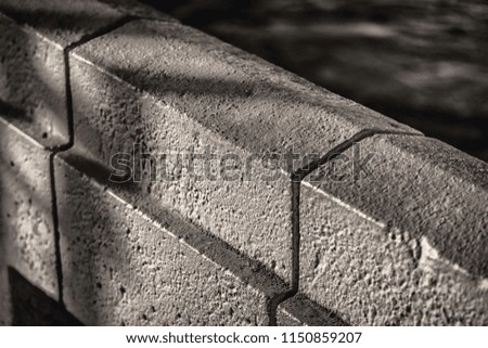 angled black and white picture of a painted cement block wall shot late in the afternoon
