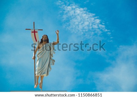 Statue of Jesus and sky,Tomb of St. Michael's Cathedral ,It is the largest Christian community in Thailand.The statue of Jesus holds the flag and waving to the man, in Tha Rae, Thailand.