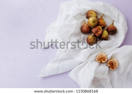 Figs on white linen against purple/lavender background.
