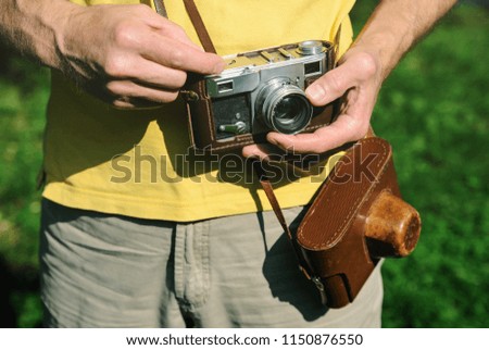 A man is holding a vintage camera. One of his hand is setting the lens.