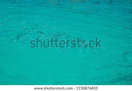 Water background: splashes of water in an outdoor aqua pool of the color of light sea wave