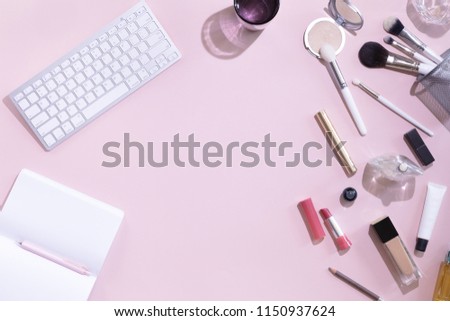 Top view of woman beauty blogger working desk with computer or laptop, notebook, decorative cosmetic, leaves shadows and hard light, envelope on pink and white pastel table. Flat lay background.