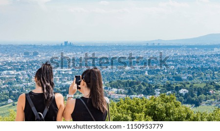 two young tourist girls taking pictures  of vienna panorama 
