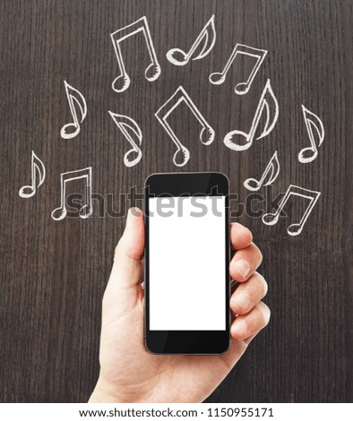 Hand holding empty white mobile phone with notes on wooden background. Music and device concept. Mock up 