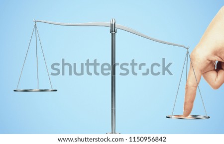 Tip the scales of justice concept. Finger illegaly influencing the legal system for an unfair advantage on blue backdrop. Royalty-Free Stock Photo #1150956842