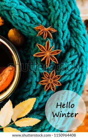Winter, fall leaves, hot steaming cup of glint wine and a warm blue scarf on wooden table background. Seasonal, winter hot wine, Winter relaxing and still life concept. Text hello winter.
