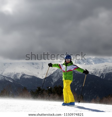 Happy young skier with ski poles in snowy sun mountains and cloudy gray sky before blizzard. Caucasus Mountains. Hatsvali, Svaneti region of Georgia. Square photo.