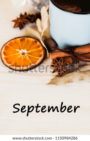 Autumn, fall leaves, hot steaming cup of glint wine on wooden table background. Seasonal, autumnal hot wine, Autumn relaxing and still life concept. Top view with text september.
