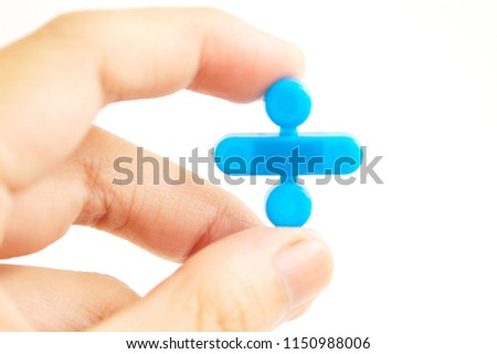 Human hand holding a division, a mathematical symbol, made of plastic over a white background. The image intentionally showing concept of mathematics education.