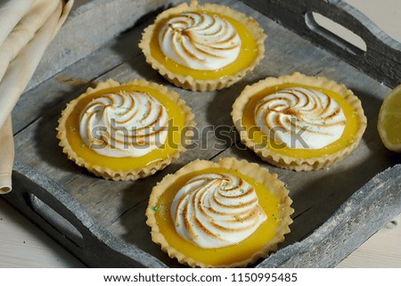 Delicious lemon tartlets with meringue on a white vintage plate.