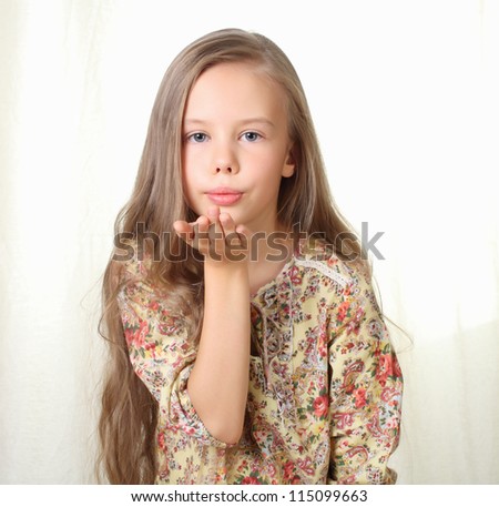 Little blond girl sends air kiss and blowing