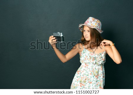 beautiful smiling child (girl) with white teeth holding a camera and making selfie