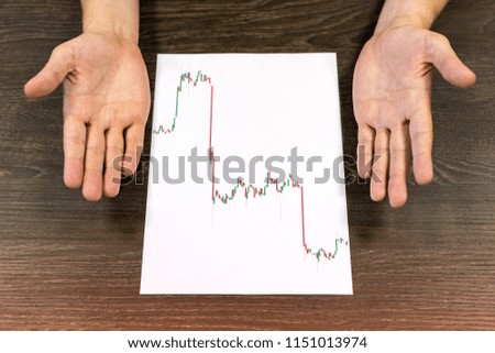 Businessman sitting at table. There are sheet of paper with a trading chart on the table. Misunderstanding gesture with hands. Concept photo.