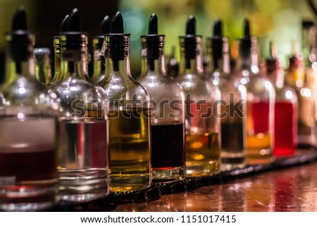 Bottles filled with syrups for mixing cocktails on bar counter. Alcohol drinks ingredients. Professional cocktail liquors. Horizontal image with selective focus.  Royalty-Free Stock Photo #1151017415