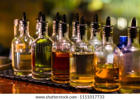 Bottles filled with syrups for mixing cocktails on bar counter. Alcohol drinks ingredients. Professional cocktail liquors. Horizontal image with selective focus.  Royalty-Free Stock Photo #1151017733