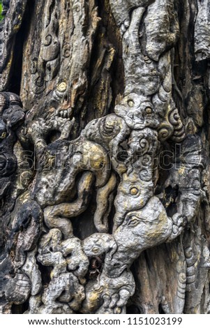 An old carved of animal in fairy tail of Thai cultural around the dead tree.
