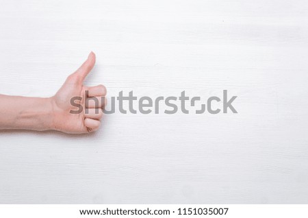 Woman hands showing a thumbs up gesture isolated on white wooden background.