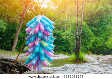 Colorful of Cotton Candy ,Place near the tourist attraction.,There is a green forest in the background.,Add an orange light to the beautiful picture.