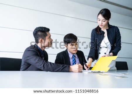 Confident businessman sitting at table and signing paperwork of his partner and smiling after making profitable agreement.