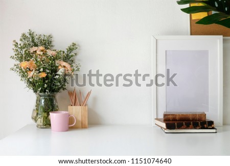 Stylish workspace with poster, book and flower bouquet. Workplace desk and copy space.