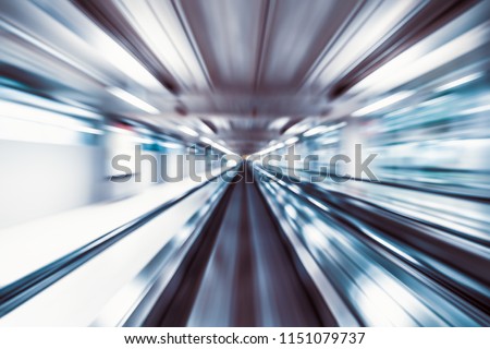 Motion blur abstract background, fast moving walkway or travelator in airport terminal transit, zoom effect, center diminishing perspective. Transportation, warp speed, or business technology concept Royalty-Free Stock Photo #1151079737
