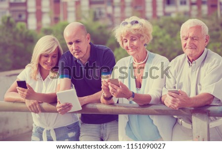 mature friends chatting in phones in the outdoor