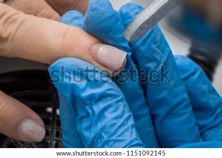 manicure, the master filings nails with a nail file