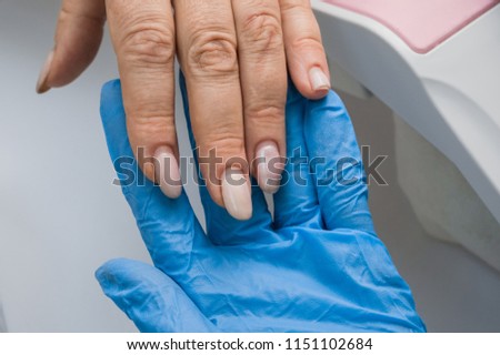manicure, the master filings nails with a nail file