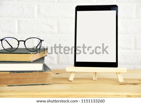Blank screen tablet,glasses and book
on the wood table
