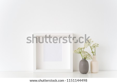 Interior white square frame mock up with a episcopal weed in vases near white wall. Mockup for quote, promotion, headline, design. Template for small businesses, lifestyle bloggers, social media