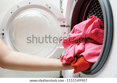 Photo of woman hands folding things in washing machine