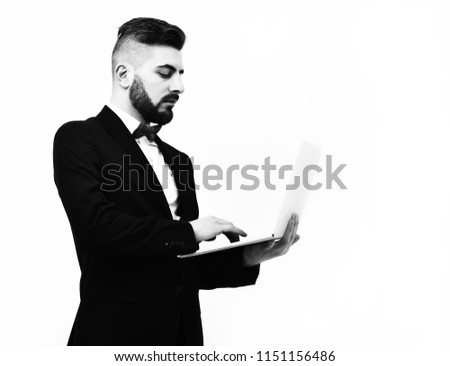 isolated on white background, copy space. Concept of technology and business, Businessman with beard or director with serious face holds computer in hands and looks at it with concentration,