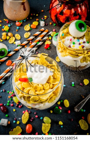 Funny Halloween food ideas, trifle dessert for kids, with spooky Halloween decorations and candies, dark background