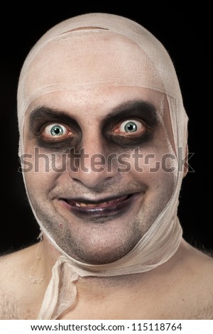 Funny zombie with bandages around his head. Young man portrait with zombie make up