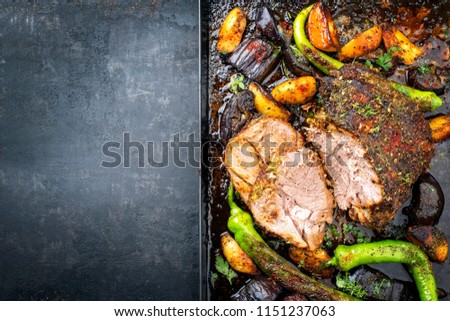Barbecue marinated lamb roast with vegetable and potatoes as top view on a metal sheet with copy space left